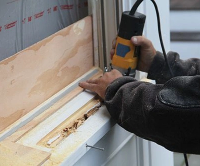 Close-up of a technician treating wood rot and splicing new timber into a classic Wooden Window Repair sill