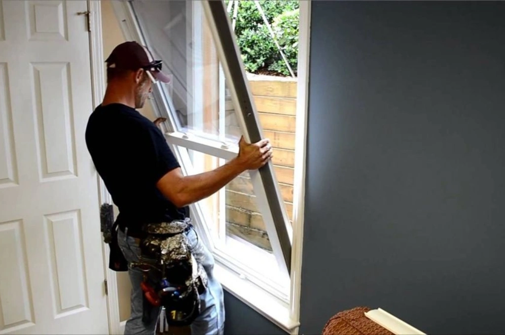 Uniformed RHS Window Repair technician fixing an aluminium window frame in a Gibraltar apartment.