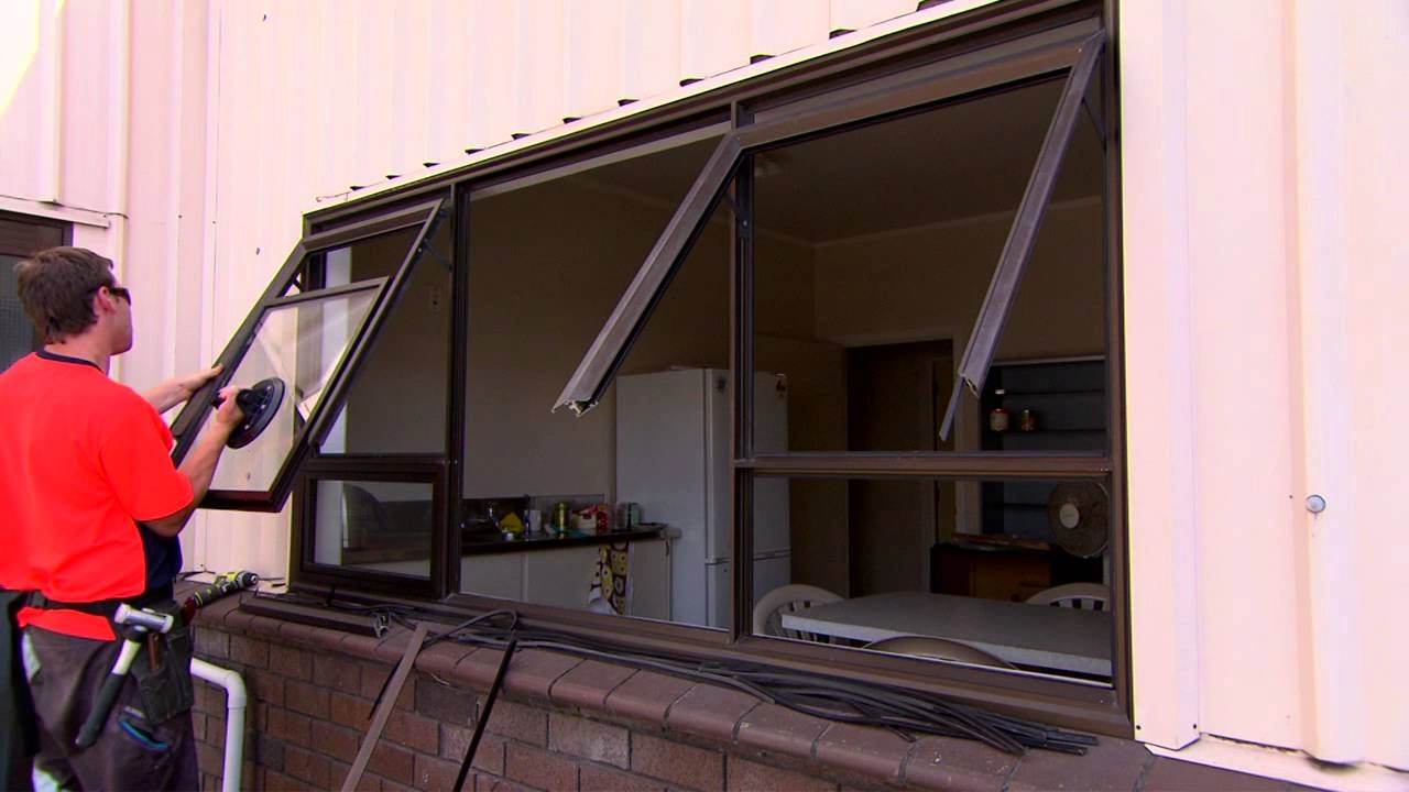 Expert RHS technician carefully removing a foggy, blown double-glazed glass repair unit from a modern UPVC frame in Gibraltar's Ocean Village.